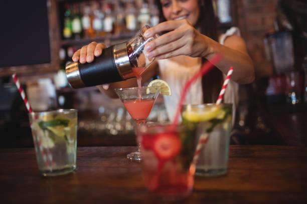 istock Pretty bartender pouring a cocktail drink in the glass 677461140