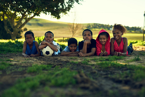 Shot of a group of children lying together with a soccer ball on some grass outside