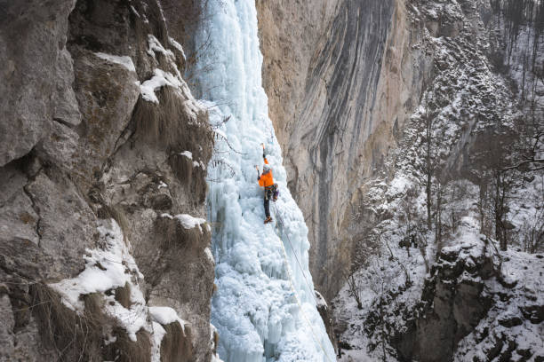 istock Male alpinist ice climbing on frozen cascade 677468952