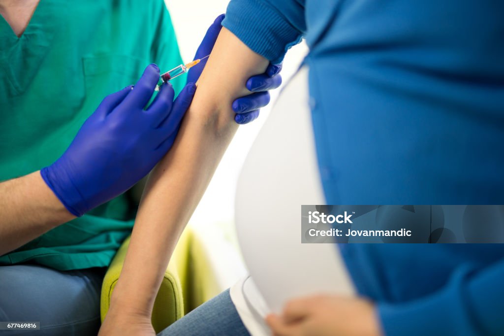 Doctor vaccinating young pregnant woman Vaccination Stock Photo