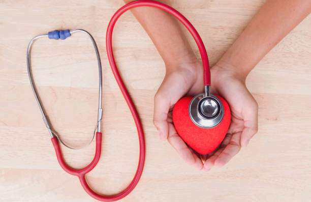 istock Medical stethoscope and heart and hand on table background 677505334