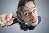 Young man is looking through magnifying glass. View from above.