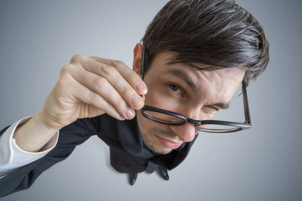 Young skeptic man with glasses is looking at you. View from above.