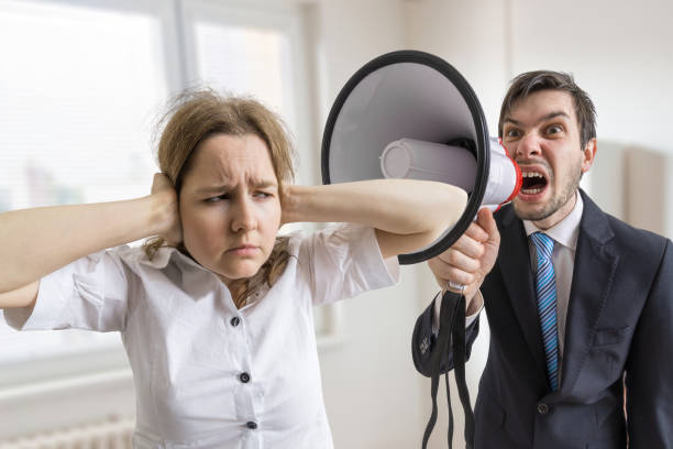 istock Mobbing at work. Manager is shouting at his secretary at work with megaphone. 677529620