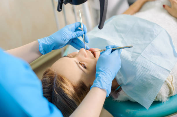 Female dentist treating caries using microscope at the dentist office