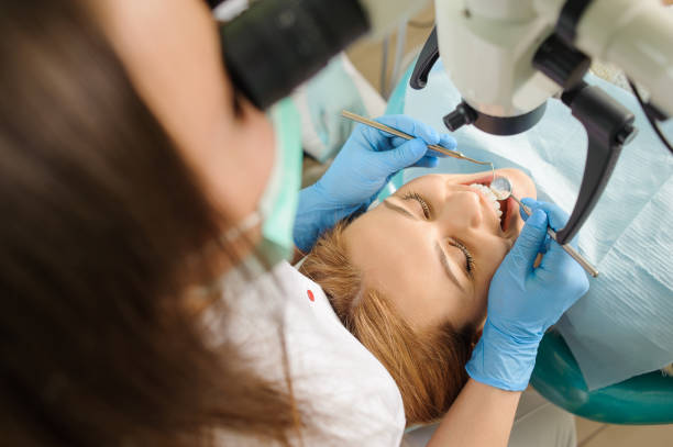 istock Female dentist treating caries using microscope at the dentist office 677581714