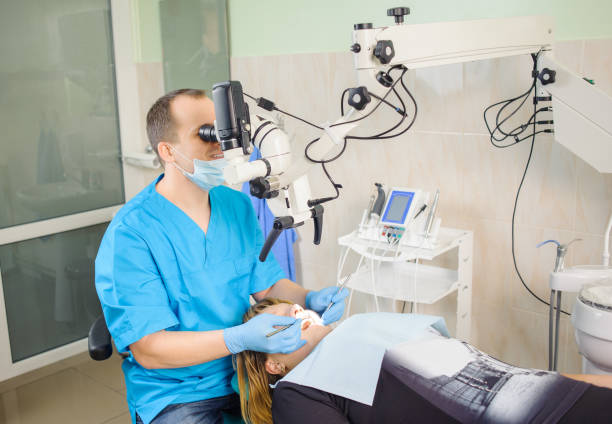 istock Male dentist working with microscope at modern dentist clinic 677607060