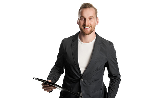 Handsome man in business casual clothing standing holding a clipboard, in front of a white background.