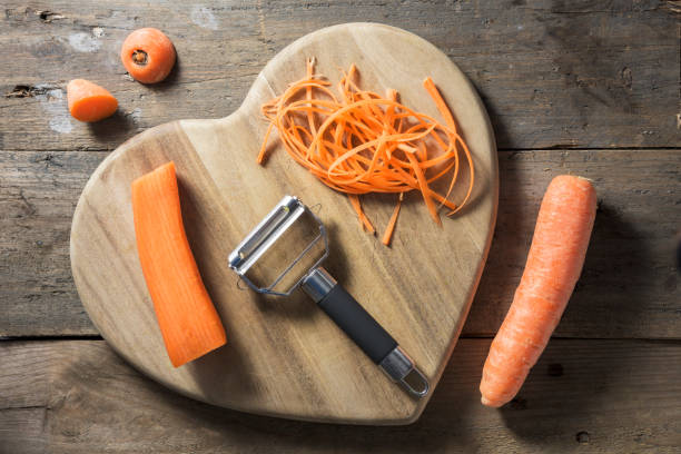 Strands of julienned carrot on a heart shaped chopping board