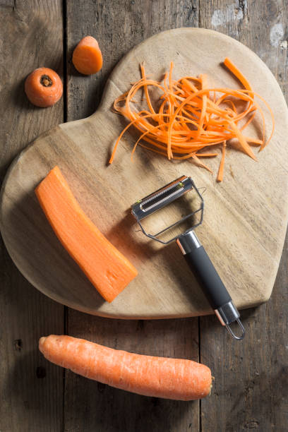 istock Strands of julienned carrot on a heart shaped chopping board 677619082