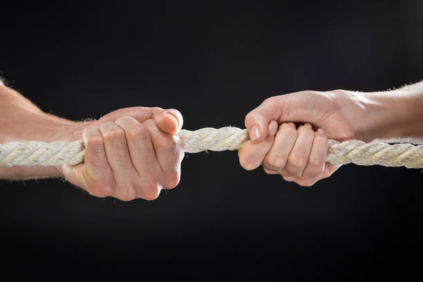 istock cropped view of man and woman pulling rope isolated on black 677638624
