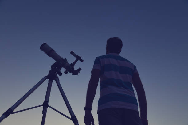 istock Man looking at the night sky through a telescope. 677639060