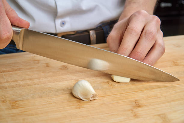 istock Man's hands cutting fresh garlic in the kitchen, preparing a meal for lunch. 677639284