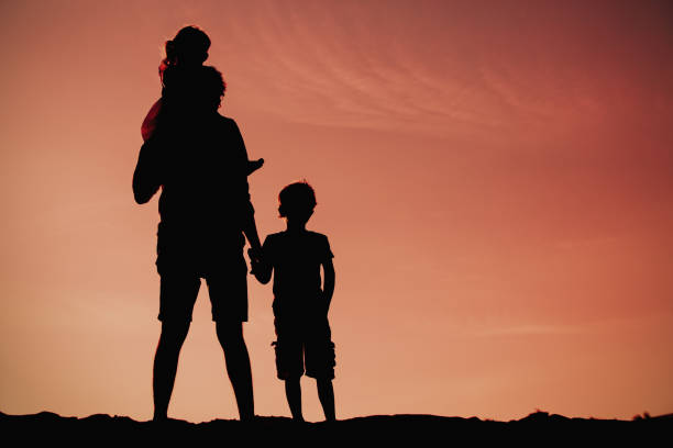 istock father with son and daughter silhouettes walk at sunset 677639512