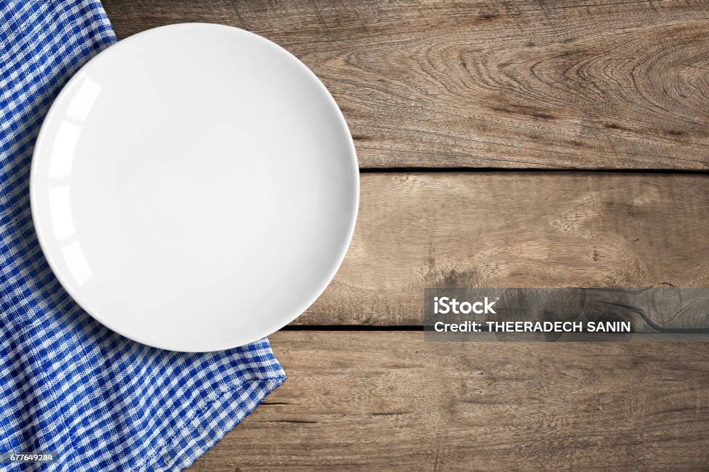 Blank Dish Top view of blank white dish and blue tablecloth on a wood background with copy space. Table Stock Photo