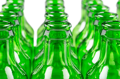 Vertical view of an empty beer glass with some green glass beer bottles.