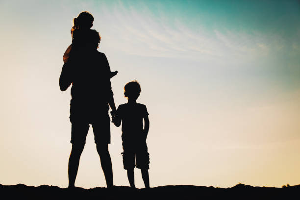 istock father with son and daughter silhouettes walk at sunset 677662164