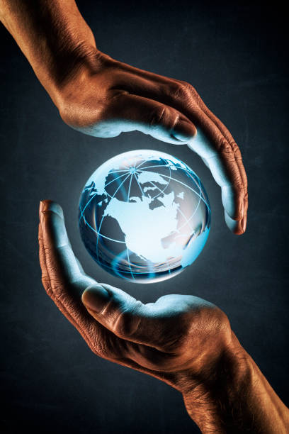 Photography of a female and male hand surrounding a blue glowing glas globe.