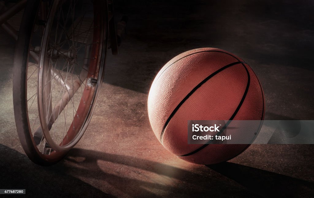Basketball und Rollstuhl in einer einsamen Atmosphäre im Konzept Enttäuschung, Verletzung, Mutlosigkeit, Verzweiflung - Lizenzfrei Rollstuhl-Basketball Stock-Foto