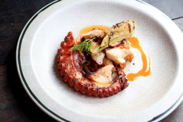 istock Grilled octopus tentacles with lemon and parsley leaves on dish. 677711590