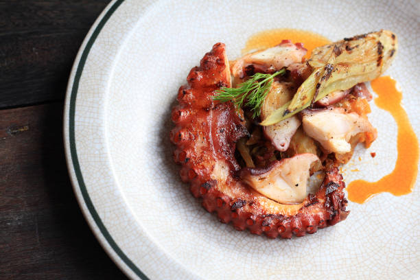 istock Grilled octopus tentacles with lemon and parsley leaves on dish. 677711612