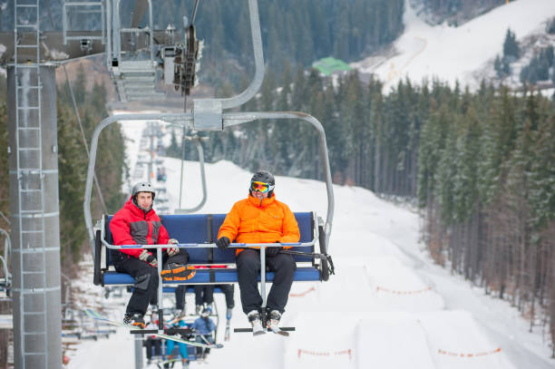 istock Skier and snowboarder riding up on ski lift 677749854