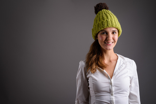 Studio shot of beautiful woman wearing knitted hat against gray background horizontal shot