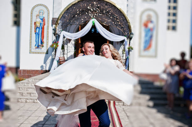 istock Groom holding bride on hands after wedding ceremony at church. 677787918