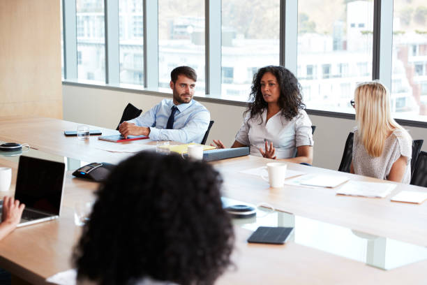 istock Businesswoman Leads Meeting Around Board Table 677809580