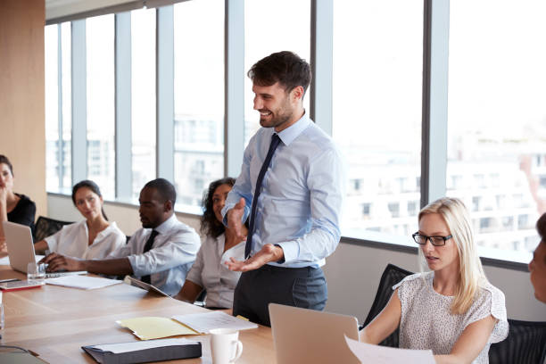 istock Businessman Stands To Address Meeting Around Board Table 677809746
