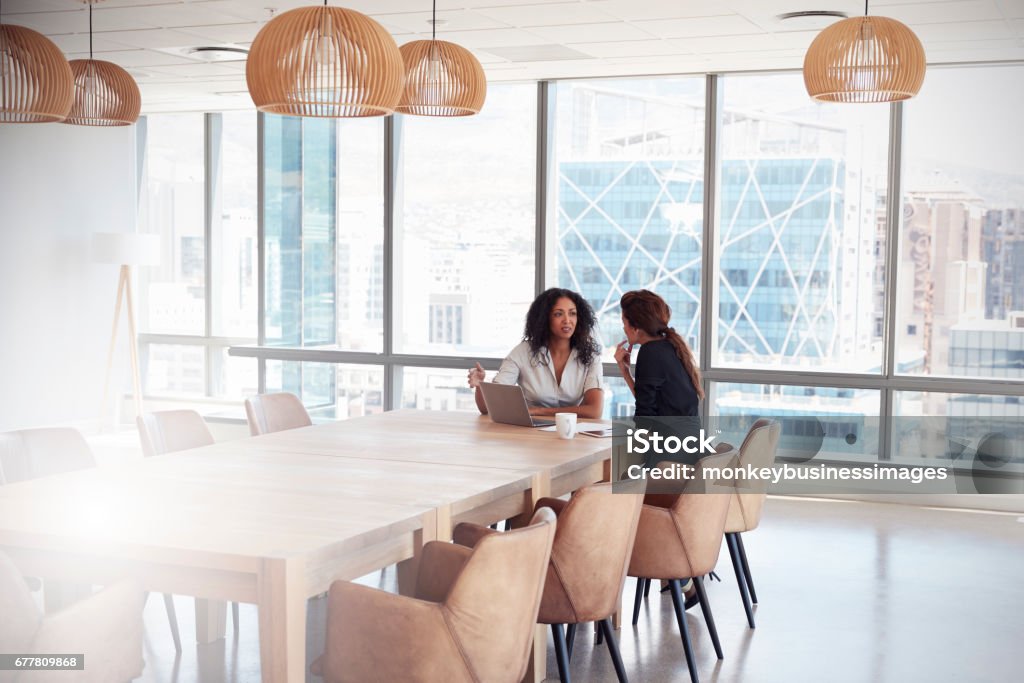 Two Businesswomen Using Laptop In Boardroom Meeting Two People Stock Photo