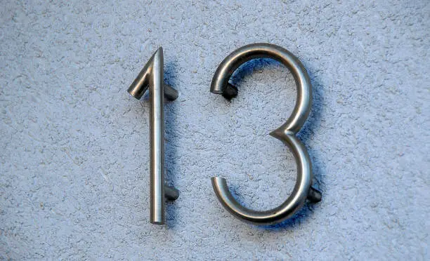 housenumber 13 made from metalic numerals on a blue wall