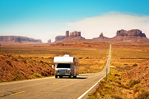 A Recreational Vehicle RV camper driving on the highway at the scenic Monument Valley Tribal Park in Arizona, USA. A famous scenic tourist destination in the southwest USA. The iconic western landscape is a backdrop for many western movies.