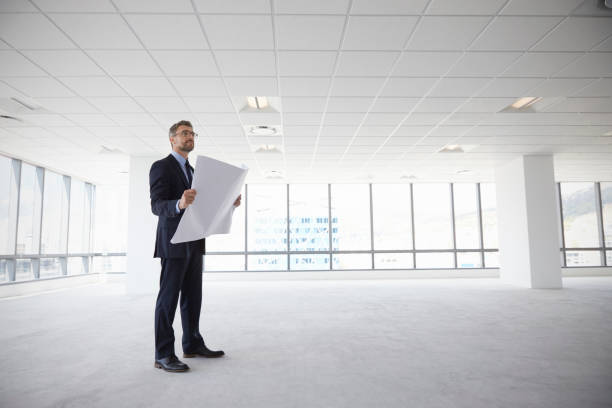istock Male Architect In Modern Empty Office Looking At Plans 677893360