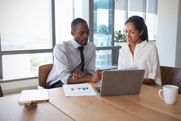 businesspeople working on laptop in boardroom together - computer two people asian ethnicity women imagens e fotografias de stock