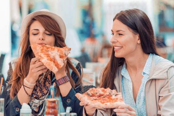 istock Two cheerful  girls eating pizza 677908434
