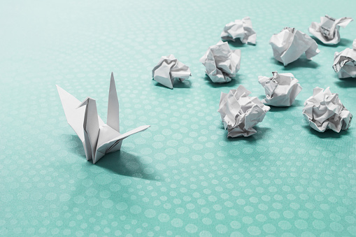 Concepto del éxito, Un pájaro de papel del origami y bolas de papel arrugadas photo