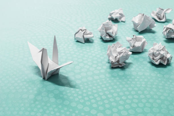 conceito de sucesso, um pássaro de papel origami e bolas de papel amassadas - failure - fotografias e filmes do acervo