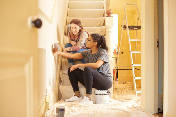 female couple choosing swatch colours a female same sex couple have a chat on the stairs to discuss which colour to paint the woodwork in their new home restoring home improvement house home interior stock pictures, royalty-free photos & images