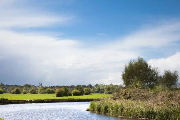 Photo of chilly springtime sun on famous beauty spot of River Stour with Dedham church in distance in Essex England