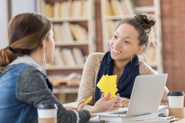 Diverse female college students use notecards in campus library