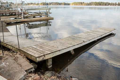 A wooden dock has been damaged and footings shifted from the ice during the winter months.
