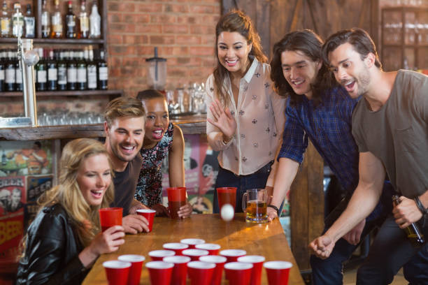 istock Friends cheering while woman playing beer pong in bar 677944588