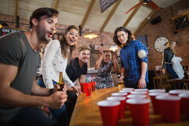 istock Young friends enjoying beer pong game in restaurant 677945124