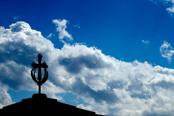 Bamberg, Bavaria / Germany - Mar 12, 2020: Close up of metal cross on top of one of the four towers of Bamberg cathedral (Bamberger Dom). Blue sky background.