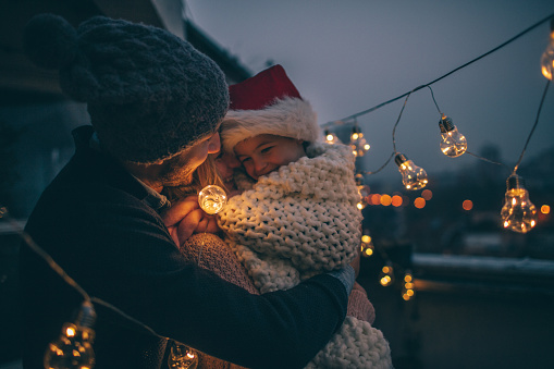 Young family enjoying together at the terrace of their apartment during Christmas holidays