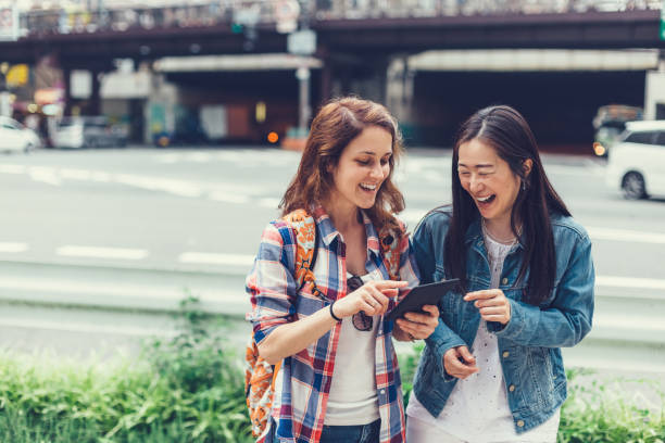 通りでタブレットを使用して東京で幸せな女性 - 観光 ストックフォトと画像