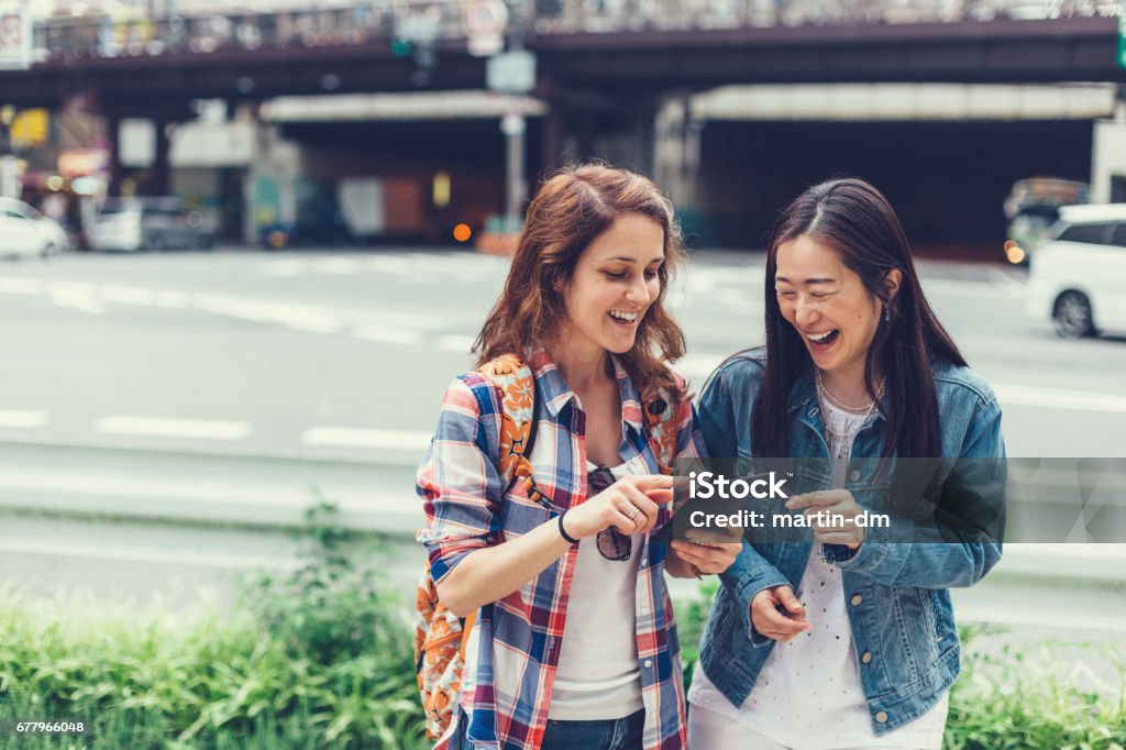 Happy women in Tokyo using tablet at the street Friends using digital tablet and laughing Tourist Stock Photo