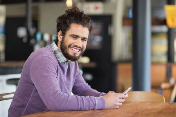 Portrait of man using mobile phones while sitting in restaurant