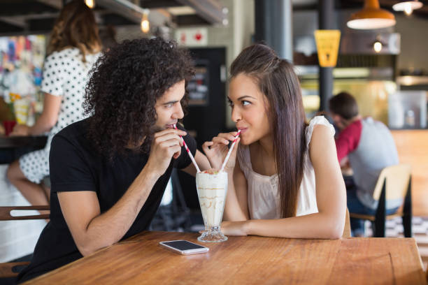 istock Young couple looking at each other while having drink together in restaurant 677978822